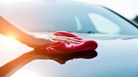 Woman hand drying the vehicle hood with a red towel
