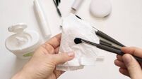 Cleaning makeup brushes with special disinfecting cloth. Hand holds the tool and wipes it.