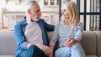 Mid age couple enjoy conversation sitting on sofa in living room