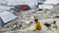 A Palestinian child sits amid the rubble of buildings destroyed in previous Israeli strikes, ahead of a ceasefire set to take ef