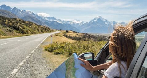 Portrait of young woman in car looking at map